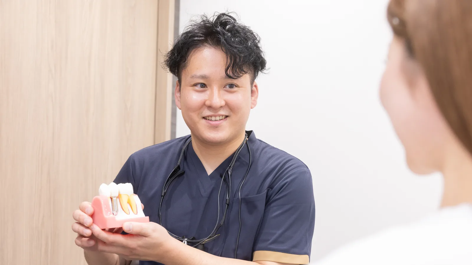 院長が歯の模型を手に、詰め物・被せ物の違いを説明している様子